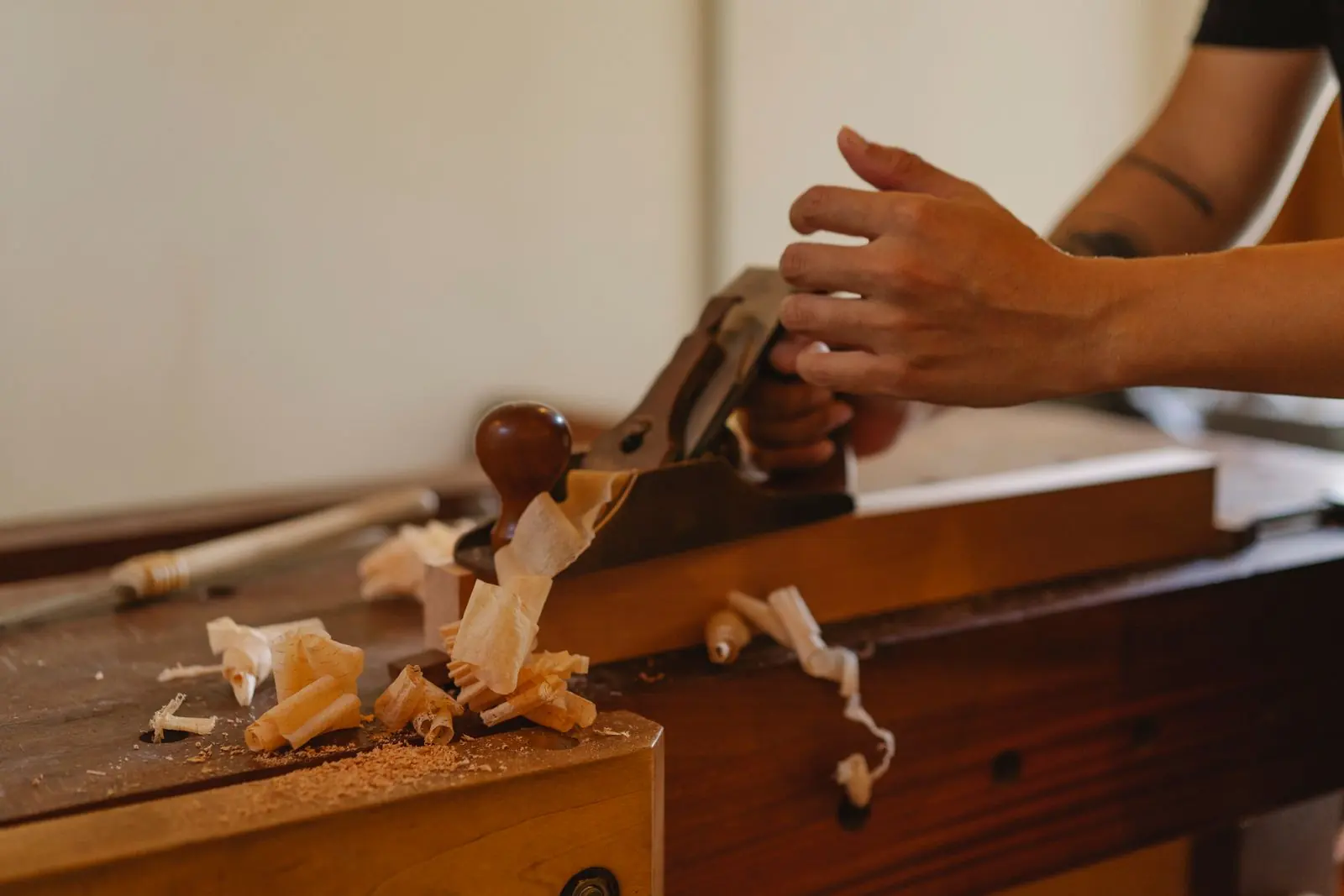 Mãos de marceneiro usando uma plaina, a marcenaria tradicional